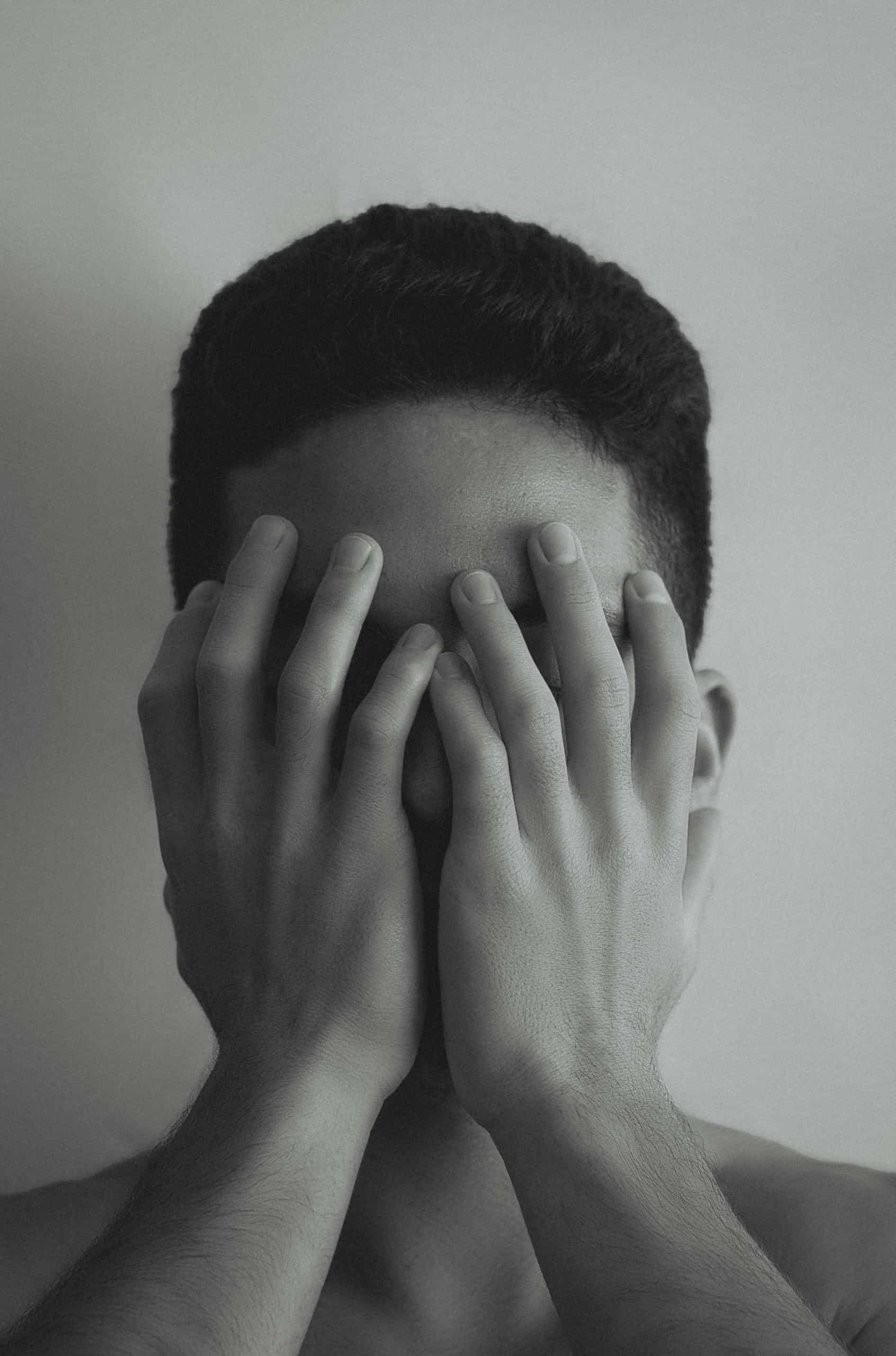 Young Man Covering His Face with His Hands